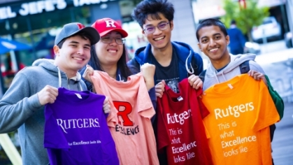 Five students holdingRutgers t shirts in a variety of colors.