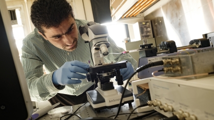 Male professor working with microscope in lab.