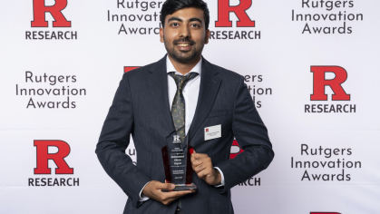 Male student wearing a suit holds an award. 