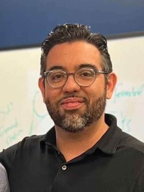 Head shot of male with short black hair, a beard and a moustache wearing eyeglasses.