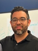 Head shot of male with short black hair, a beard and a moustache wearing eyeglasses.
