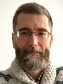 Head shot of male with short hair, full beard and eyeglasses.