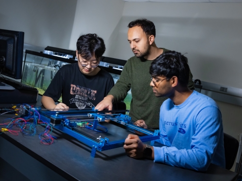 Male professor working with two male students in a lab.