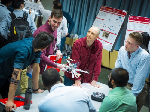 A group of male students present their design project to a judge.