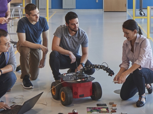 Female professor working with robotics alongside her students. 