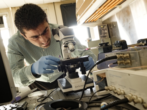 Male professor working with microscope in lab.
