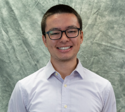Headshot of Asian male with short black hair, wearing black horn rimmed, and light colored button down shirt.